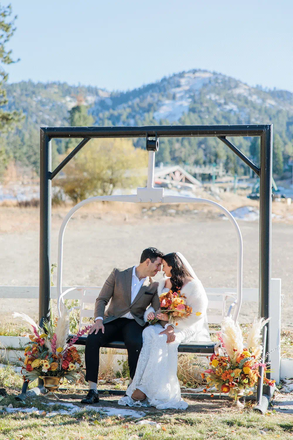 Bridge and groom staring at each other sitting on a detached chairlift with geronimo ski trail in the background